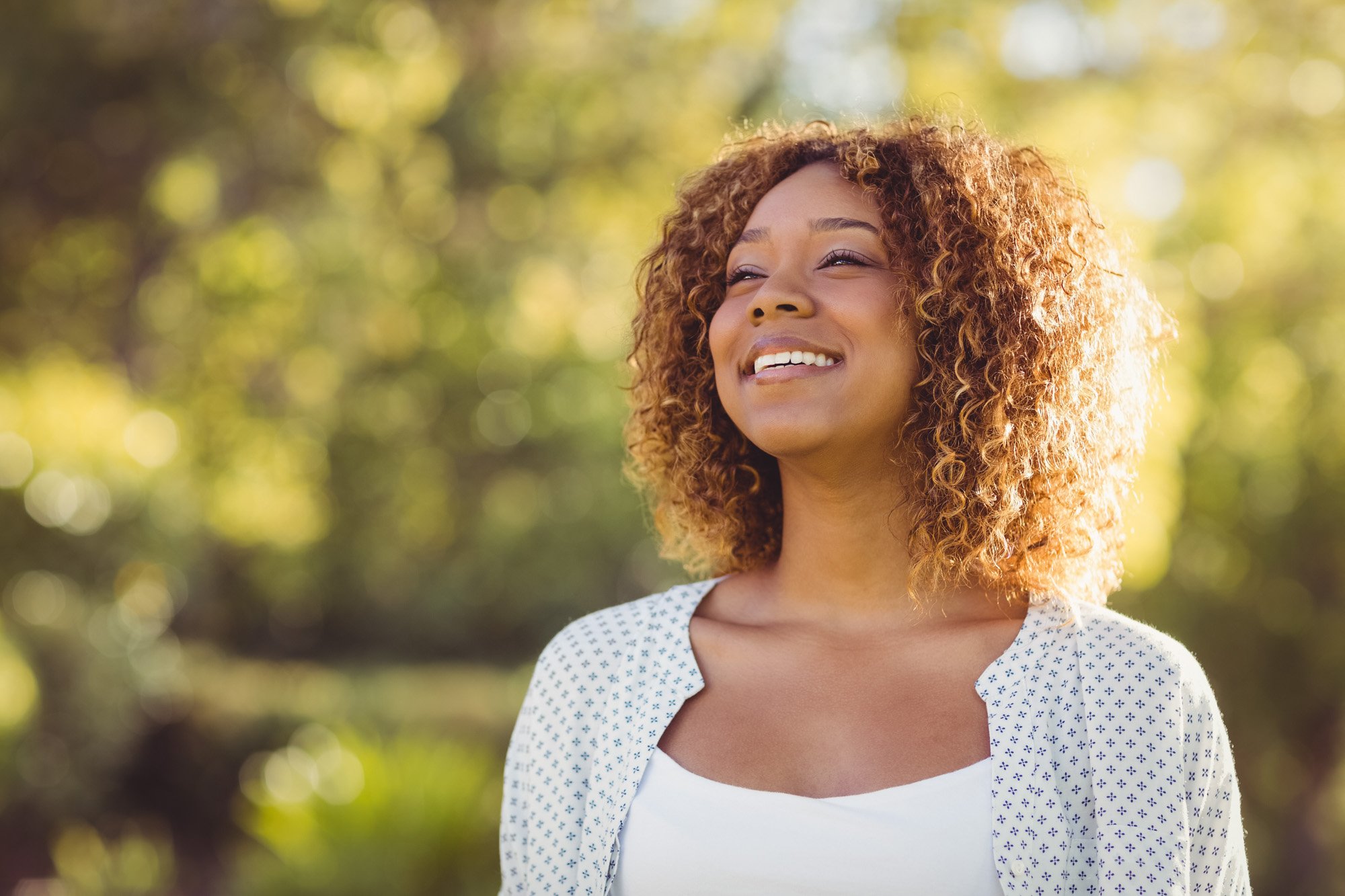 A woman smiling outdoors in warm evening light